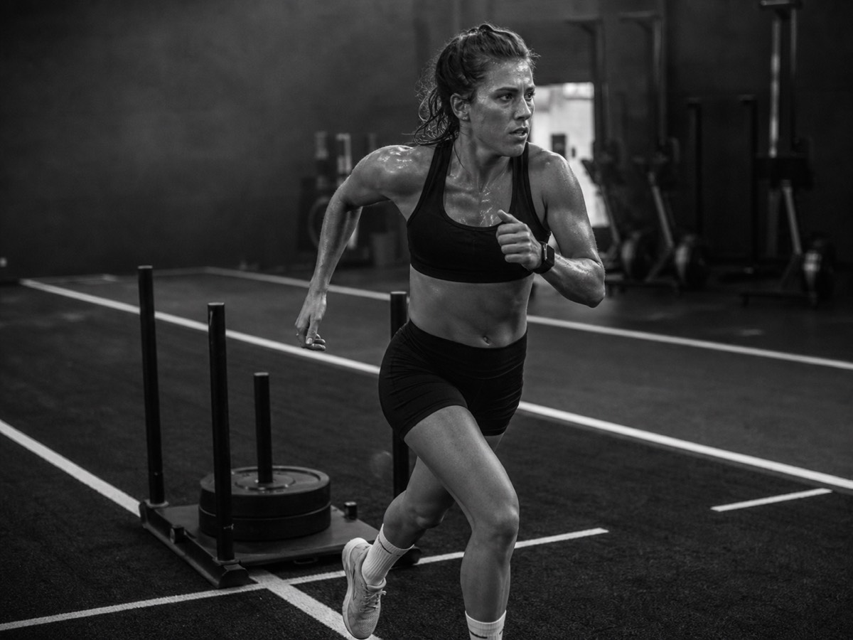 An athlete running past a loaded sled in a dark gym